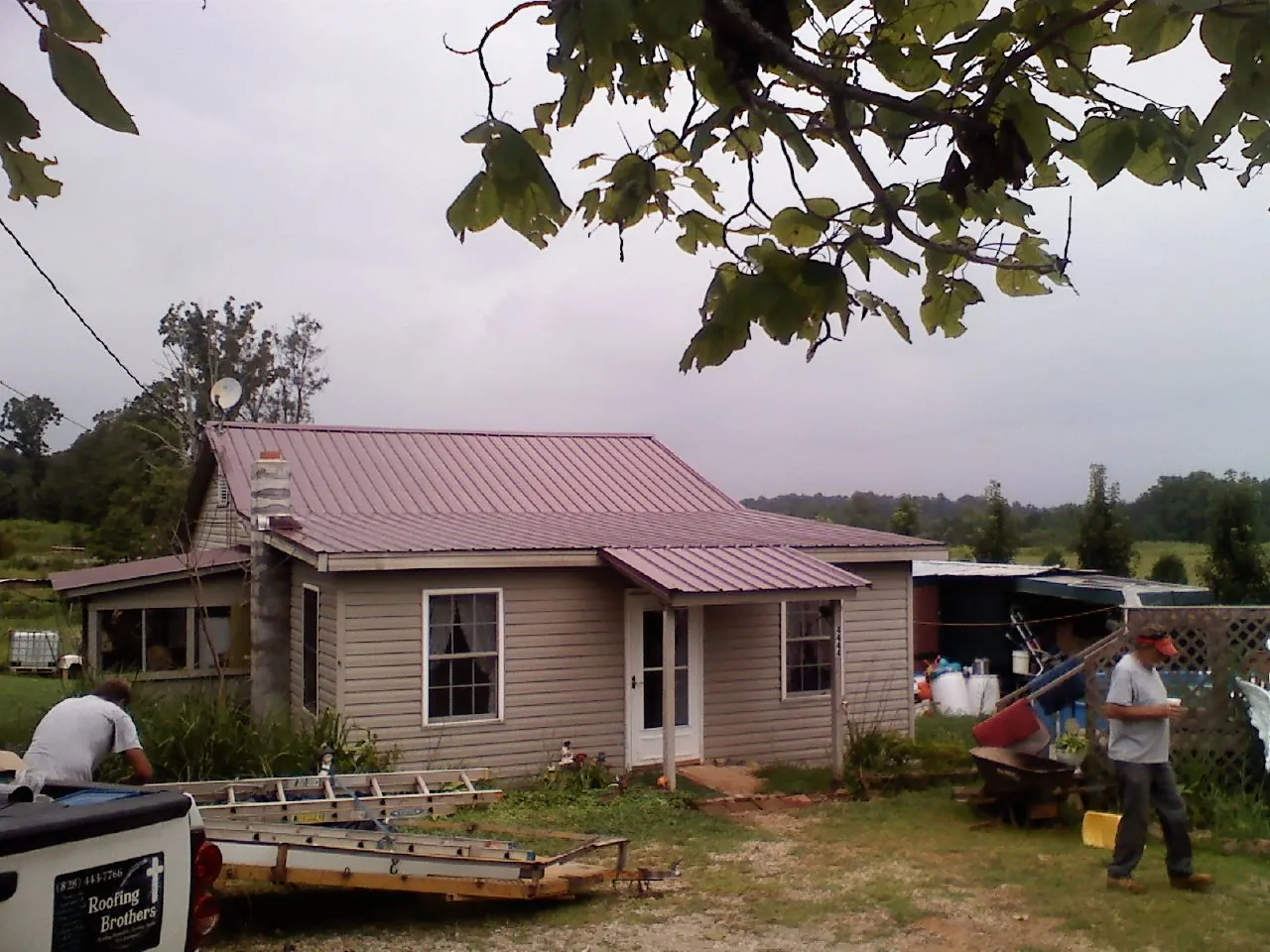 Crew finishing a mauve metal roof on a small farmhouse in Otter Creek