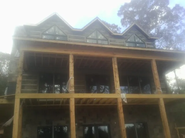 Dormers and porch framing on a large log home under construction — Roof Coating work by our crew in Otter Creek