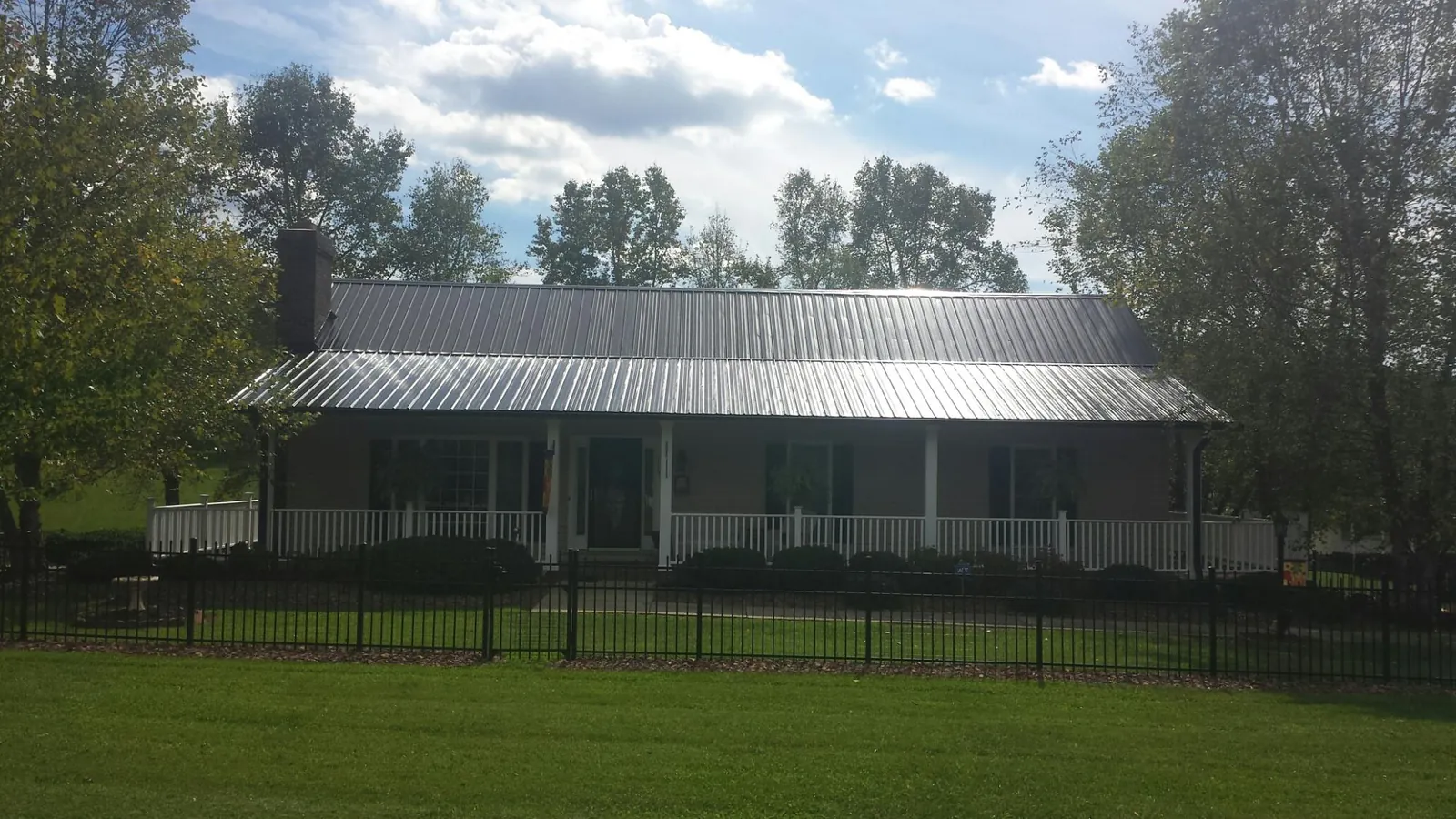 Gray metal roof on a brick ranch with a full width front porch — Gutter Guard Installation work by our crew in Otter Creek