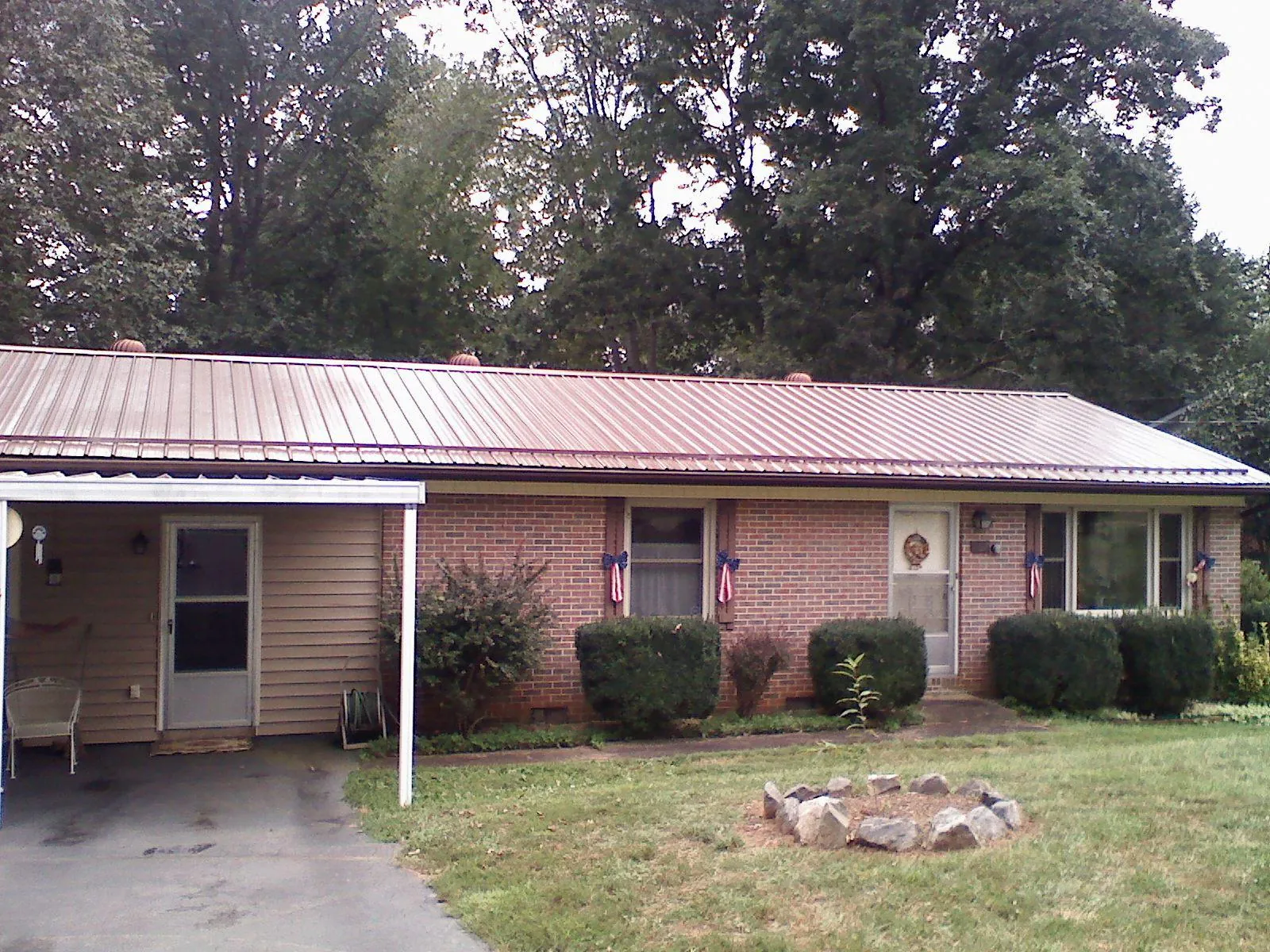 Bronze metal roof and carport on a brick ranch home — Roof Repair work by our crew in Otter Creek
