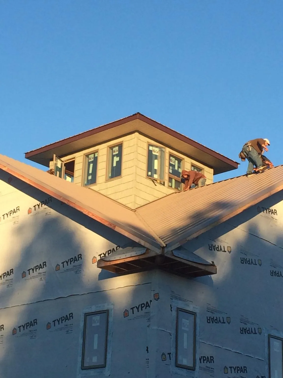 Roofers working around a rooftop cupola on a new metal roof at sunset — Roof Waterproofing in Otter Creek by Roofing Brothers